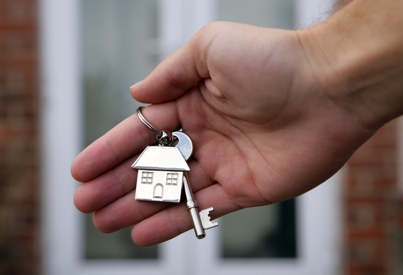 Hand holding key and keyring of house